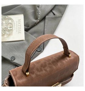Macro shot of brown suede handbag featuring golden hardware and multi-layer inner structure