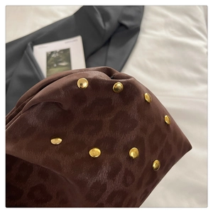 Dettaglio di borsa leopardata con borchie dorate e trama in pelle liscia fine