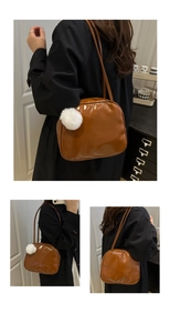Detail of glossy caramel patent leather backpack with white fluffy ball charm accessory