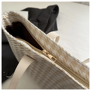 Detailed close-up of herringbone weave texture and premium gold zipper on beige tote bag