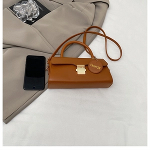 Détail d'un sac à bandoulière marron vintage avec fermoir doré et étiquette mode
