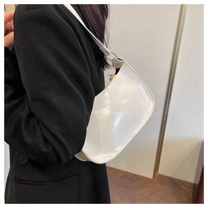 Detail of a white glossy faux leather underarm bag showing its smooth texture and curved shape