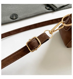 Detail of dark brown suede bag strap with adjustable gold buckle and metal swivel hook