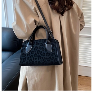 Close-up of leopard print handbag with black leather trim and adjustable shoulder strap