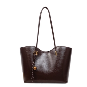 Dark brown faux leather tote bag with glossy finish and decorative bell pendant charm