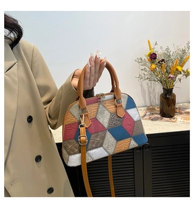 Detail of geometric patchwork shell bag with multi-color leather textures and gold hardware