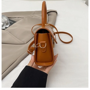 Vue détaillée du sac bandoulière marron caramel avec finitions dorées et design accordéon