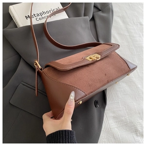 Detail of vintage caramel brown leather bag with suede patchwork and gold twist lock