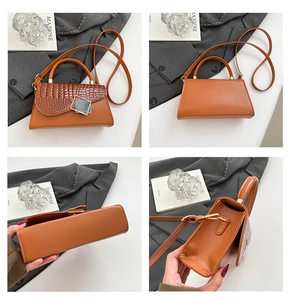 Detail view of orange-brown crossbody bag showing croc-embossed texture and metal buckle