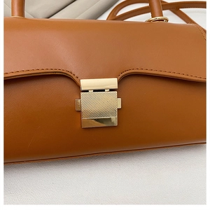 Détail d'un sac bandoulière en cuir marron avec un fermoir rectangulaire en métal doré
