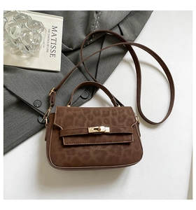Detail of leopard print suede crossbody bag with gold metallic clasp on white surface