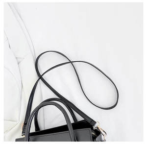 Dettaglio borsa tote nera minimalista con manici lucidi e dettagli in metallo oro