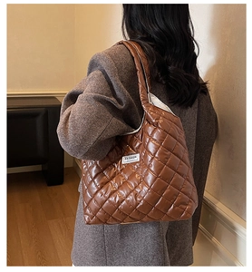 Detail of a brown quilted tote bag with glossy finish and 'FASHION' label on side