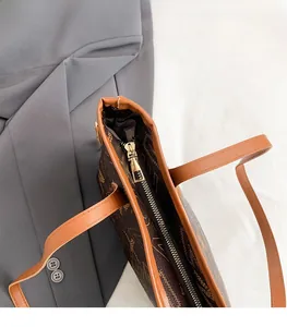 Dettaglio della cerniera dorata liscia e della trama monogramma sulla borsa tote grande
