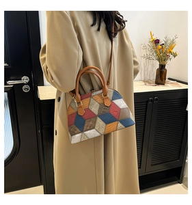 Détail d'un sac bandoulière géométrique multicolore porté sur un élégant manteau beige