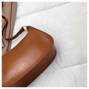 Close-up of caramel brown leather handbag with vintage oil-wax texture and gold buckle