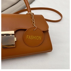 Détail du sac bandoulière marron caramel avec fermoir doré et pendentif fashion