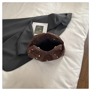 Dettaglio della pochette leopardata con borchie dorate e chiusura magnetica su panno