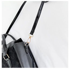 Dettaglio della borsa in pelle nera con inserti in pelle scamosciata e finiture dorate