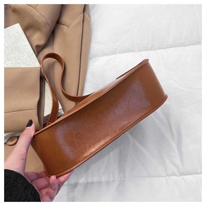 Detailed view of caramel brown faux leather underarm bag with vintage textured finish