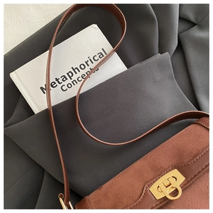 Detailed shot of brown suede and leather patchwork bag with gold circular metal clasp