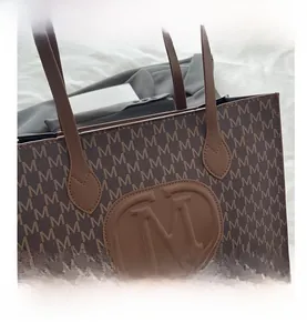 Close-up of brown tote bag featuring detailed M letter print and embossed logo emblem