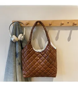 Close-up of brown quilted puffer tote bag with glossy finish hanging on a wooden hook