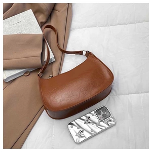 Detailed texture of caramel brown oil-wax leather on a retro crescent shoulder bag