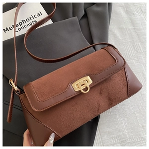 Detail of brown suede and leather baguette bag with golden twist lock and thin strap