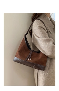 Detail of a brown suede shoulder bag with contrast stitching and leather strap for women