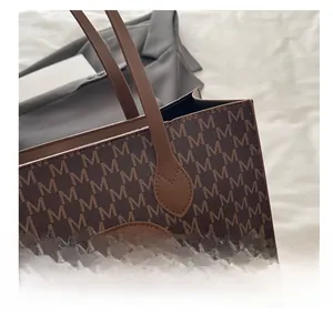 Close-up of deep brown leather tote bag with letter M monogram pattern and embossed logo