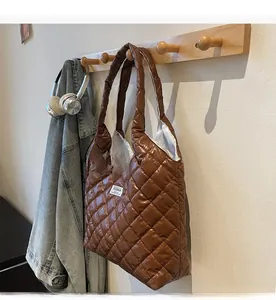 Detail of a brown quilted down tote bag with a fashion label hanging on a wooden hook