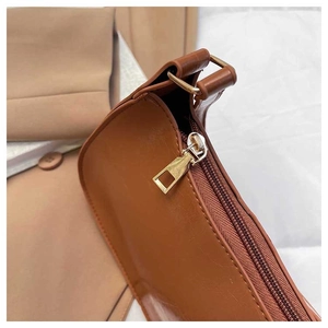 Close-up of golden metal zipper and hardware details on a brown faux leather handbag