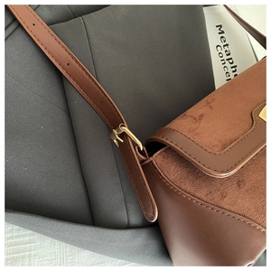 Close-up of caramel brown retro baguette bag showing leather textures and gold buckle