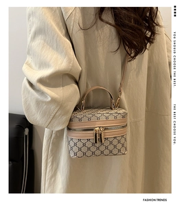 Detail view of a vintage box-style handbag with monogram pattern and leather straps