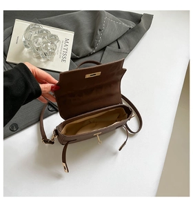 Detailed top view of the brown leather handbag with golden twist lock and beige lining