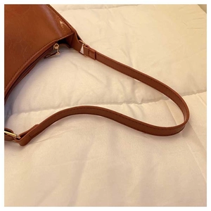 Detail of caramel faux leather shoulder bag with gold zipper and adjustable strap