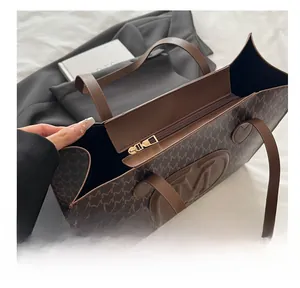 Close-up of deep brown tote bag featuring repeating M-letter pattern and embossed logo