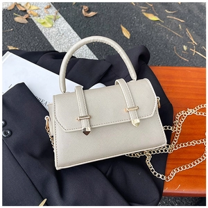 Detailed macro view of the cream leather texture and gold metal clasp on a handbag