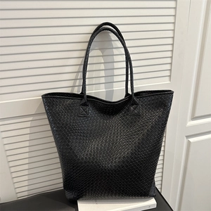 Minimalist large black tote bag featuring premium woven texture and long shoulder straps