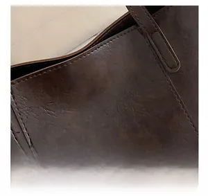 Close-up of brown PU leather tote bag featuring litchi grain texture and gold logo