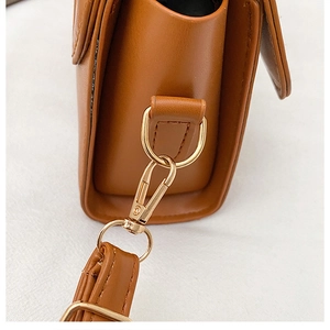 Détail du fermoir en métal doré et des coutures sur le sac bandoulière en cuir PU brun