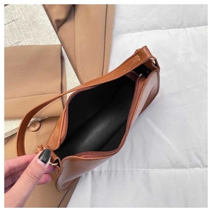 Detail view of the caramel underarm bag with zipper closure and black fabric lining