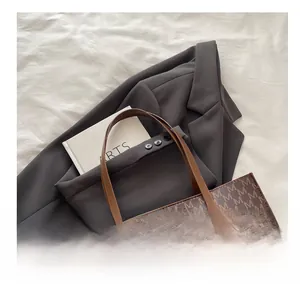 Detailed view of brown tote bag with M letter prints and circular embossed logo detail