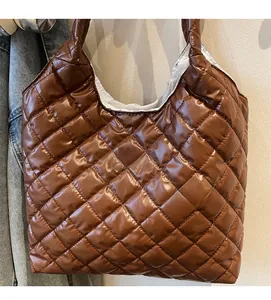 Detail of a brown quilted tote bag with a white fashion label on glossy padded fabric
