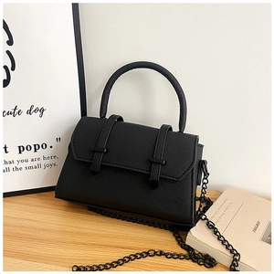 Detail of black structured crossbody bag with cross-grain leather texture and chain strap