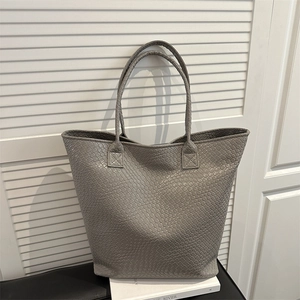 Large gray woven texture tote bag with double handles in a minimalist studio setting