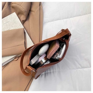 Detailed view of spacious brown handbag interior holding cosmetics and a smartphone