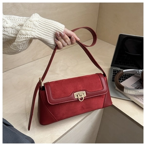 Detail of red vintage baguette bag with gold metal buckle and matte suede texture