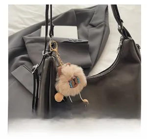 Brown fluffy cartoon plush pendant with pom-poms on a leather bag detail